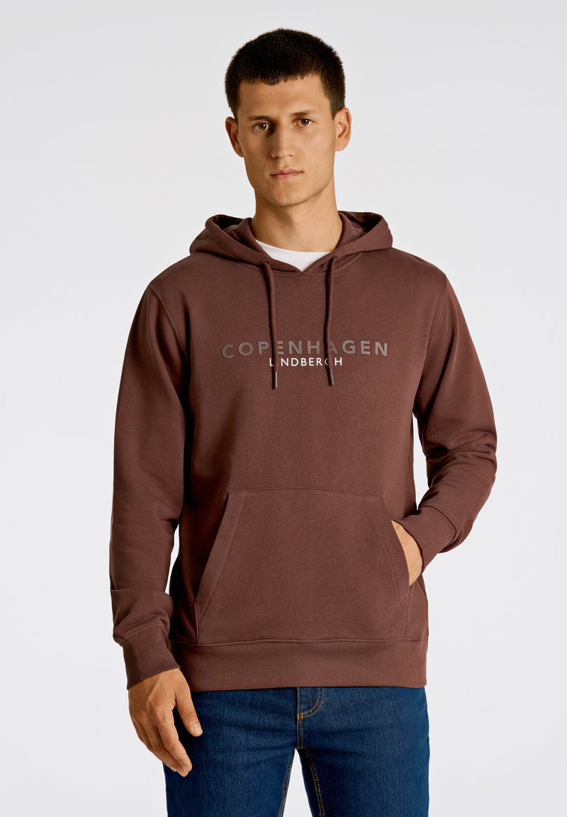 Brun huvtröja med framficka, dragsko i huva och tryckt "COPENHAGEN LINDBERGH"-logotyp. Mjuk tyg och avslappnad passform.