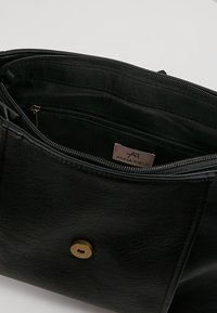 Borsa a mano in pelle nera con superficie testurizzata, scomparti con zipper e dettagli in metallo color oro. L'interno mostra la fodera.