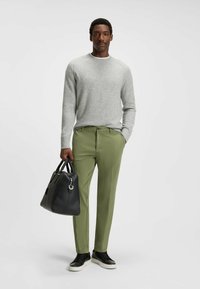 Light gray sweater, green trousers, black leather bag, and sneakers. Wool material, ribbed cuffs, tailored fit, and smooth textures.