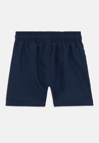 Μακριά μαγιό με ελαστική μέση σε ναυτικό μπλε χρώμα, κατασκευασμένα από ελαφρύ ύφασμα, με λεία υφή και χωρίς ορατά σχέδια ή διακοσμήσεις.