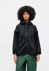 Μαύρο μπουφάν με φερμουάρ και κουκούλα, με λεία εξωτερική επιφάνεια, ελαστικά μανσέτα και αντίθετο σχεδιασμό με υφή σε πάνελ στο στήθος.