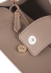 Interno di una borsa in pelle grigia con un vano con zip e chiusura a scatto con un accento metallico dorato. Texture liscia e cuciture dettagliate.