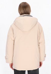 Beige gewatteerde jas met capuchon, voorzien van een grijze kraag en verstelbare manchetten. Het ontwerp heeft een eenvoudige, gladde textuur en een oversized pasvorm.