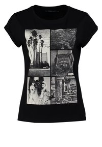 Camiseta de algodón negra con un collage de imágenes en blanco y negro, que incluyen palmeras, una cámara y escenas de la calle, con mangas enrolladas.