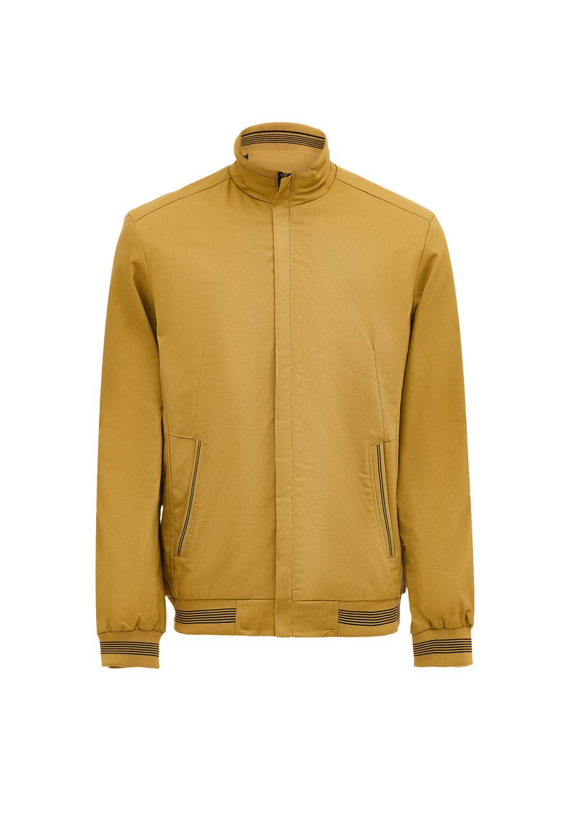 Giacca gialla senape con colletto alto, due tasche frontali con zip, polsini elasticizzati e una texture semplice. Accenti a righe orizzontali sui polsini.