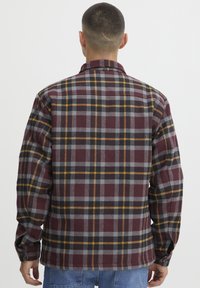 Geruite flanellen shirt met een bordeauxrood, grijs en geel patroon. Lange mouwen met knoopsluitingen en een rechte zoomdesign.