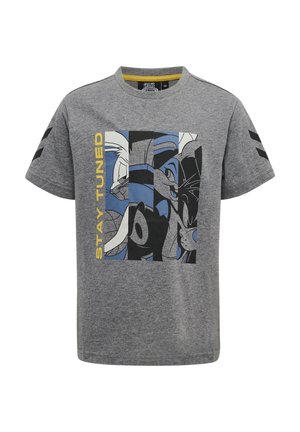 Camiseta gris de manga corta con caras de dibujos animados estilizadas en negro y azul y texto amarillo "STAY TUNED" en el frente. Cheurones negros en las mangas.