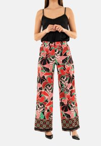 Pantalons à jambes larges ornés d'un motif floral vibrant en rouge, rose et vert sur un fond noir, avec une taille et un ourlet décoratifs.