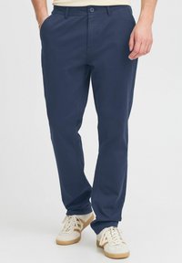Mornarji modri chino hlače iz lahkega bombaža s ravnim krojem, z stranskimi žepi in gumbastim zapiranjem spredaj.