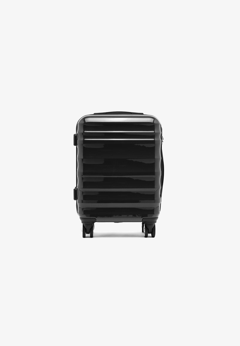 Černý tvrdý kufr s horizontálními drážkami, vrchním madlem, bočními madly a čtyřmi kolečky pro snadnou mobilitu. Hladký, reflexní povrch.