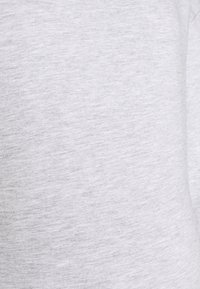 Närbild av ljusgrå tygtextur med fina horisontella fibrer och subtila nyansvariationer.