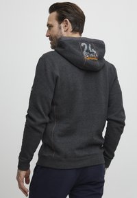 Dark gray hoodie with a large hood, contrasting orange stitching, and the number "24" embroidered on the back. Cotton blend material.