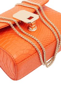 Sac à main en cuir texturé orange avec une chaîne dorée et un fermoir carré en métal. Le design présente une forme structurée et un motif en relief.