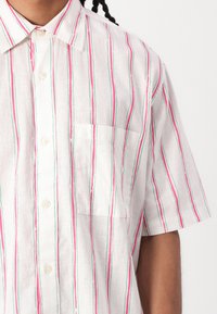 Short-sleeve shirt in lightweight fabric featuring vertical stripes in pink and green on a white background; includes a chest pocket.
