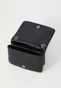 Svart läderhandväska med kviltad design, magnetisk stängning och silverfärgad metall. Har ett rymligt innerrum med en ficka utan blixtlås.