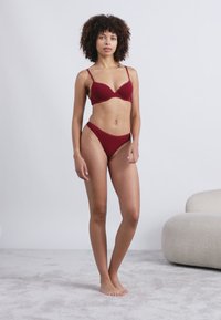 Μπραζίλ και αντίστοιχα ψηλόμεσα εσώρουχα με κορδόνι σε μπορντό απόχρωση. Μαλακό, ελαστικό ύφασμα, χωρίς ραφές, ελάχιστα μεταλλικά στοιχεία και λεία υφή.