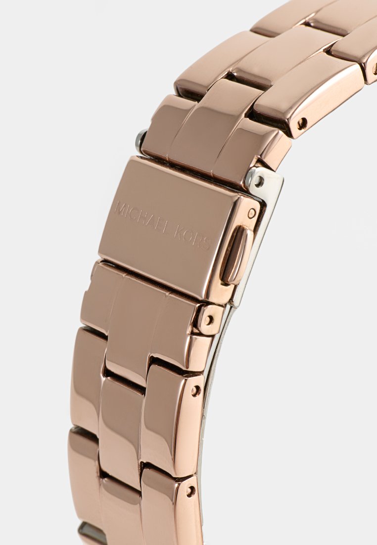 Michael Kors Uhr mit einem Armband aus roségoldfarbener Metall, das eine glatte, polierte Oberfläche aufweist und einen Verschluss mit eingraviertem Branding beinhaltet.