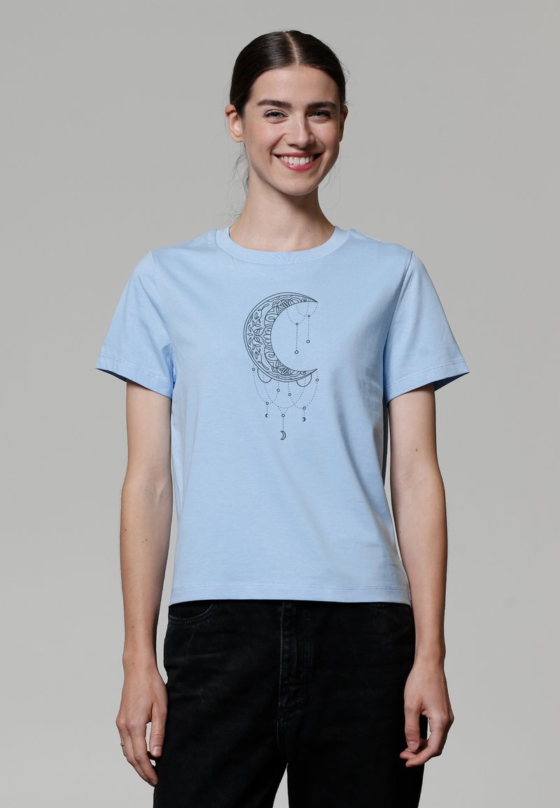 T-shirt en coton bleu clair avec un graphique de croissant de lune noir et des accents suspendus. Manches courtes et design à col rond classique.