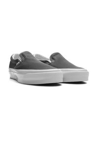 Scarpe slip-on in tela grigia con suola in gomma bianca, caratterizzate da cuciture a vista e un design a taglio basso per una facile vestibilità.