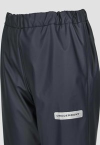 Marineblauwe waterdichte broek met elastische tailleband, gladde textuur en een zilveren "SWEDEMOUNT" logo aan de zijkant.