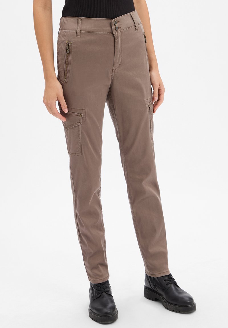 Pantalons cargo en tissu marron clair avec une coupe slim, dotés de poches zippées et de subtils accents en métal. Texture lisse et design fuselé.