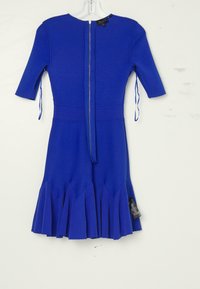 Robe bleue mi-longue avec manches trois-quarts, ourlet plissé, liens latéraux et fermeture éclair centrale dans le dos, présentée sur un cintre transparent sur fond blanc.