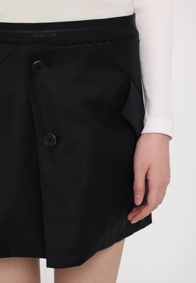 Melnā svārku nesamais gludā auduma, ar augstu vidukli, diviem priekšējiem pogām un sānu kabatu. Dizains ir minimālistisks un pielāgots.