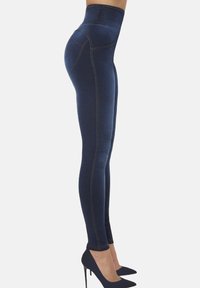 Legginsy w kolorze ciemnoniebieskim z wysokim stanem, dopasowanym kroju, z subtelnymi detalami szycia, wykonane z elastycznego materiału, zestawione z czarnymi, spiczastymi obcasami.