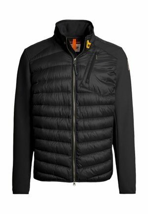 Veste noire avec un devant matelassé et des manches en tricot texturé. Comprend un col montant et une poche poitrine zippée.