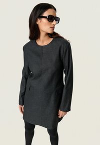 Sötétszürke csíkozott ruha kerek nyakkivágással, hosszú ujjakkal és oldalsó zsebekkel. Az anyag sima tapintású és strukturált formájú.