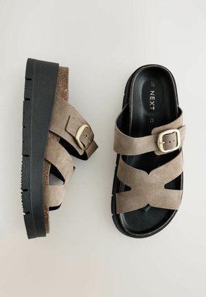 Brown suede platform sandals with crossed straps, a metal buckle detail, and a textured black rubber sole. Smooth footbed.