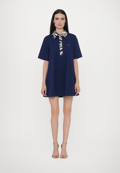 Abito corto navy con colletto a fantasia e dettaglio con fiocco. Il design presenta maniche corte e una vestibilità ampia, realizzato in tessuto leggero.