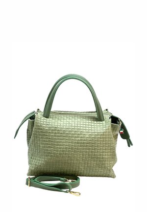Sac à main tissé vert clair avec deux poignées et une bandoulière assortie amovible avec des fermoirs dorés sur fond blanc.