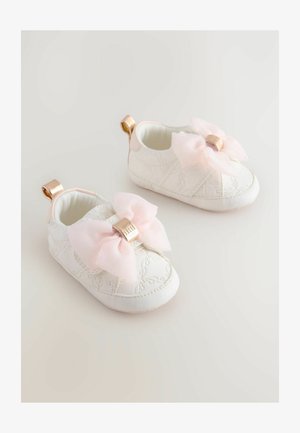 Bele čevlje za dojenčke z quiltiranim dizajnom, okrašeni z veliko roza pentljo in zlatim poudarjanjem. Vključuje zanko na zadnji strani za enostavno obuvanje.