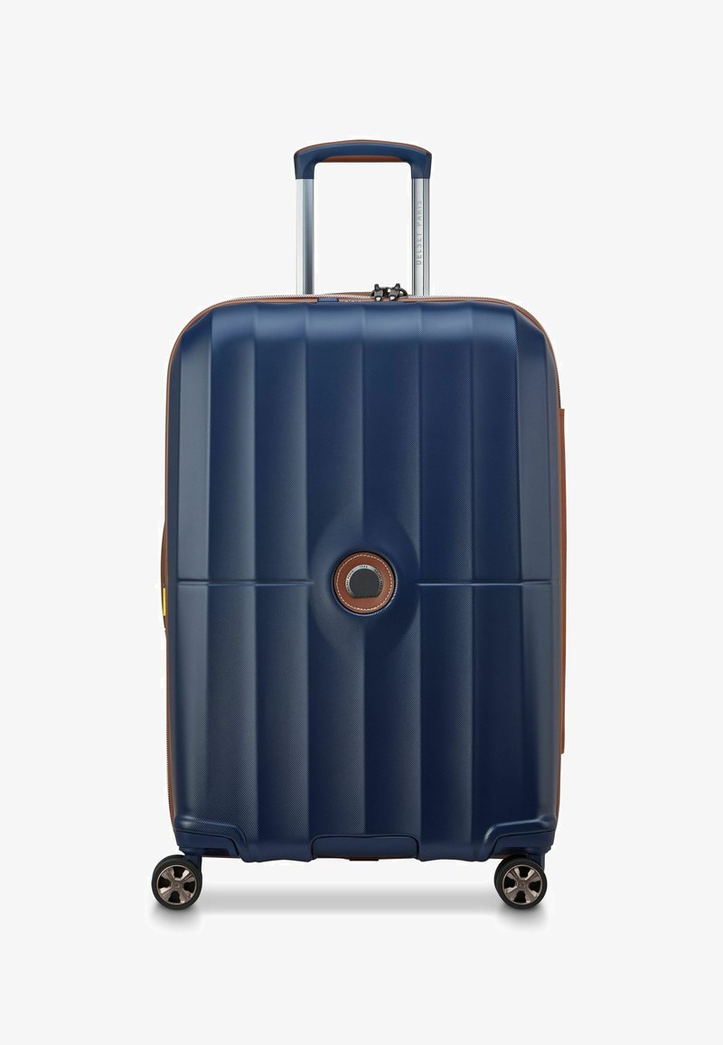 Valise rigide bleu marine à quatre roues, poignée télescopique et logo circular au centre à l'avant.