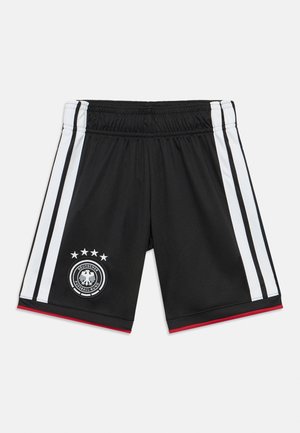 Calças de treino pretas com riscas laterais brancas, detalhes em vermelho e um emblema da federação alemã de futebol com cinco estrelas e uma águia.