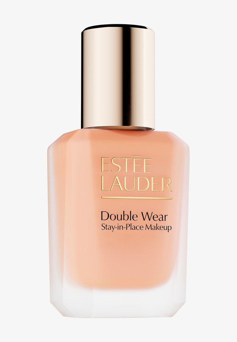 Estee Lauder Double Wear -meikkivoide kirkkaassa lasipullossa, jossa on kulmikas muotoilu. Korkki on metallinhohtoinen kulta; neste näyttää persikkasävyiseltä.