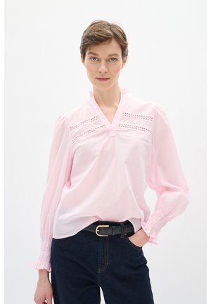 Lyserød bluse med V-udskæring, plisserede detaljer og puffede ærmer. Har indviklede blondeaftaler og en afslappet pasform. Bæret med mørke jeans.