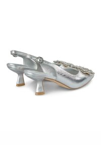Scarpe slingback metalliche argentate con punta appuntita, parte anteriore decorata e tacco a blocco di 5 cm. Texture liscia e cinturino alla caviglia regolabile.