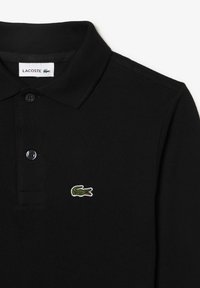 Black polo shirt made of textured fabric, featuring a two-button placket and a green crocodile logo embroidered on the left chest.