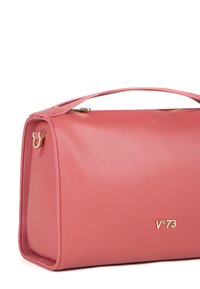 Roze leren handtas met een gestructureerd oppervlak, rechthoekige vorm, bovenhandvat, gouden hardware en een logo dat aan de voorkant is geperst.