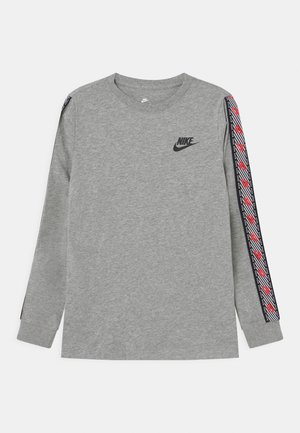 Grijs Nike-shirt met lange mouwen, met een zwart logo op de borst en decoratieve zwart-wit-rode gestreepte patronen langs de mouwen.