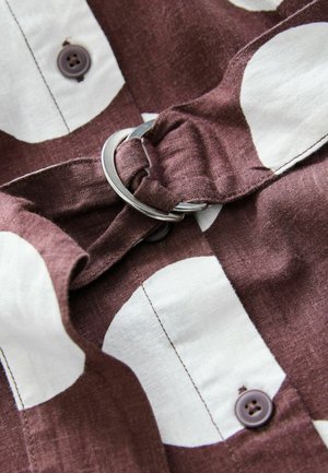 Hnědá a bílá vzorovaná látka košile se železným kroužkovým detailem a tmavými knoflíky, která vystihuje textura podobnou lnu a neformální design.