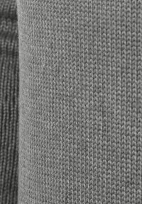 Tessuto grigio lavorato a maglia che mostra una texture liscia con un motivo uniforme e spessori variabili, caratterizzato da tonalità chiare e scure.