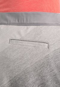 Pantalones cortos deportivos gris claro con un acabado texturizado, que presentan una cintura plana y elástica y un pequeño bolsillo horizontal en la parte posterior.