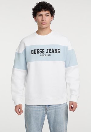 Witte sweater met lichtblauwe accenten, met "GUESS JEANS" gedrukt in vet zwart lettertype. Zachte stof en een ontspannen pasvorm.