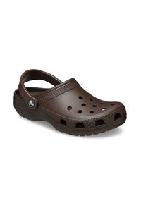 Sabot en caoutchouc marron avec des trous de ventilation, une sangle arrière et des accents à pois sur le dessus. Dispose d'une semelle extérieure texturée pour une bonne adhérence.