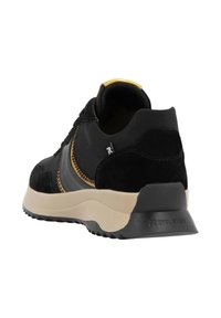 Black suede and leather sneaker with yellow stitching, cushioned beige sole, and a black heel counter featuring "REVOLUTION" branding.