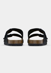 Μαύρο σανδάλι με δύο φαρδιές λουριά, πάτο από φελλό και υφή εξωτερικής σόλας από καουτσούκ. Διαθέτει μινιμαλιστικό σχεδιασμό με απαλό φινίρισμα.