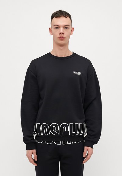 Felpa nera in misto cotone, con scollo rotondo, polsini a costine e grande testo bianco "MOSCHINO" sull'orlo.